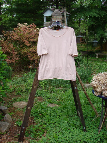 Barclay Batiste Curl Edge Layering Top Unpainted Pastel Mauve Size 1: A pink shirt with curly edges on a wooden rack.