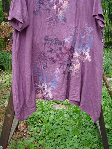 Barclay Linen Figure 8 Tunic Dress Garden Shadow Red Plum Size 2: A purple shirt on a clothesline, surrounded by green plants.