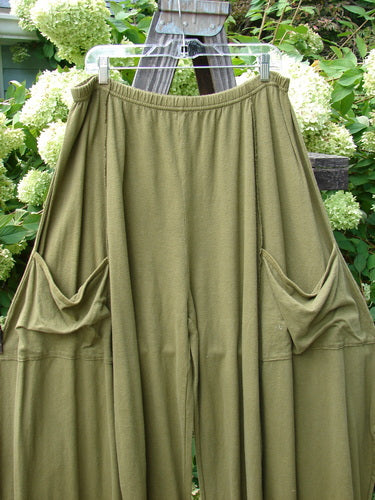 A pair of Barclay Hemp Cotton Exterior Stitch 4 Square Pants in Green Pea, hanging on a clothesline.