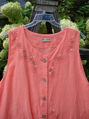 A medium weight linen Barclay Linen Katy Vest in Tangerine. Features include thick pearly buttons, varying hemline, oval neckline, painted drop pockets, and deeper arm openings. Unique revers rear upper waist seam and continuous hem neckline and front paint in the circle spin theme. Size 2.