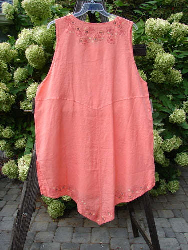 Barclay Linen Katy Vest Circle Spin Tangerine Size 2: A pink dress on a rack, featuring a unique design with thick pearly buttons, varying hemline, oval neckline, and painted drop pockets.