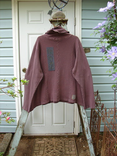 A double layered turtleneck sweater with abstract painted patches and front pockets. Size 2, loam color.