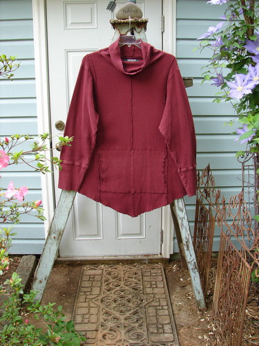 A burgundy Barclay Thermal Reverse Stitch Tunnel Pocket Top in size 2. Features include a floppy turtleneck, kangaroo tunnel pocket, and hourglass shape. Vertical sectional seams and varying hemlines add unique style. Bust 54, waist 50, hips 52. Lengths: front/back 36, sides 30.