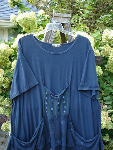 Image: A blue shirt with a pocket on a wooden rack.

Alt text: Barclay Farmer Jen Tunic Dress, navy blue shirt with pocket on wooden rack.
