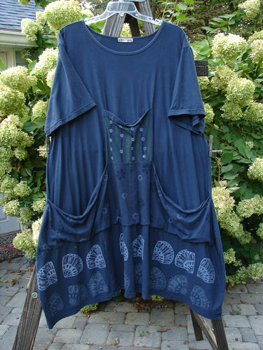 A navy Barclay Farmer Jen Tunic Dress with a shell flower theme. Generous measurements, elastic tab, oversized front drop pockets, and a bell shape. Made from organic cotton.