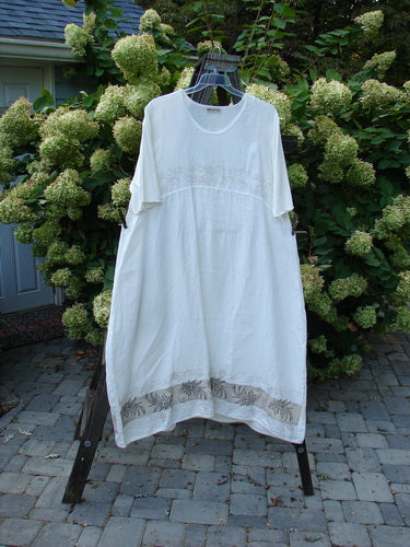 A Barclay Linen Cotton Sleeve Banded Hem Pleat Dress in White, featuring a rounded neckline, empire waist seams, and vertical pleats. Three-quarter length sleeves and a widening shape add to its unique design.