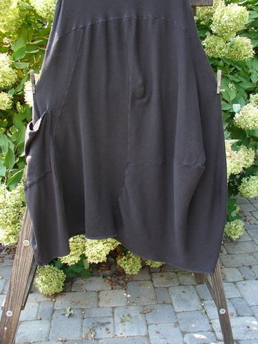 A black skirt on a wooden stand, part of the Barclay Thermal 4 Square Tulip Jumper Unpainted Storm Size 2. Cozy ribbed thermal waffle and lower rib combination, drop downward scooped slight empire waistline, huge pocketed lower bell shape, S curved seams, belled and varying hemline, deeper arm openings, and an oval neckline.