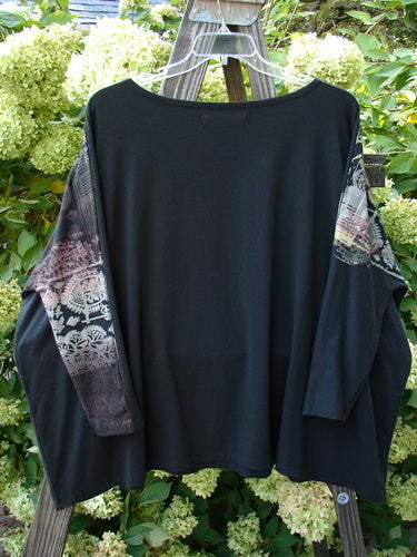 A Barclay Cotton Lycra Treesoul Top with a black floral design, featuring a boatneck rolled neckline, narrowing lower sleeves, and a wide square flair. The front showcases dynamic split metallic theme art.