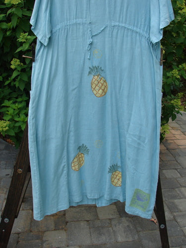 1999 Maypole Dress Pineapple Spring Size 2: A light blue dress with pineapple pattern, V neckline, thick buttons, drawstring back, and lower bushel pockets. Straight and long silhouette with bright pineapple theme paint and a blue fish patch. Bust 52, waist 52, hips 52, length 50 inches.
