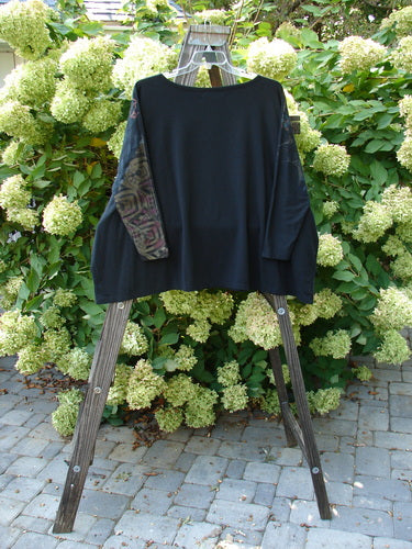 A black Barclay Cotton Lycra Treesoul Top with a wide square flair and a boatneck rolled neckline on a wooden stand.