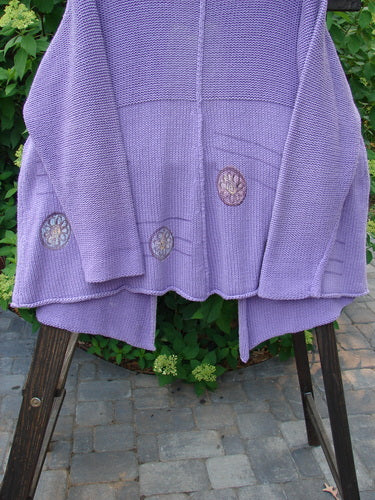 1999 Rollneck Cardigan Sweater Pinwheel Viola OSFA: A close-up of a purple sweater with lovely pinwheel patterns and a shiny porcelain button.