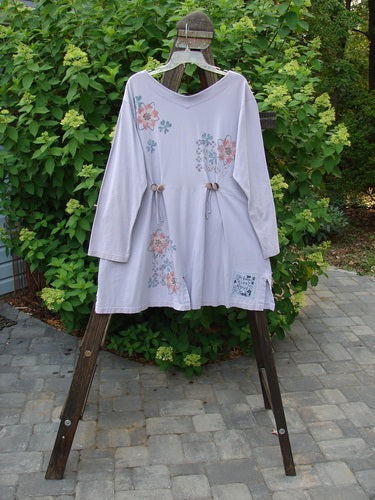 Image alt text: "2000 4 Vent Top Daisy Grid Pale Purple Size 1: White shirt with floral paint, rippie buttons, and unique vents. V-shaped neckline with triangular cotton insert and front pocket."