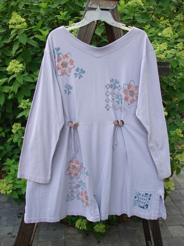 2000 4 Vent Top Daisy Grid Pale Purple Size 1: A white shirt with flowers on it, featuring a V-shaped neckline and sectional floral paint. Accented with rippie buttons and 4 unique vents.