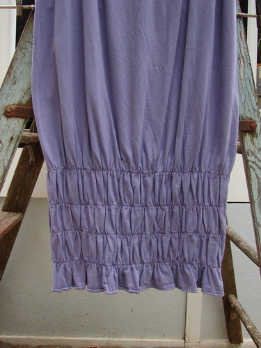 2000 NWT Rings of Saturn Skirt Unpainted Twilight Size 2: A close-up of a purple skirt on a ladder, made from light organic cotton. Features include a full elastic waistline, tapered lower, and stretchy smocking.