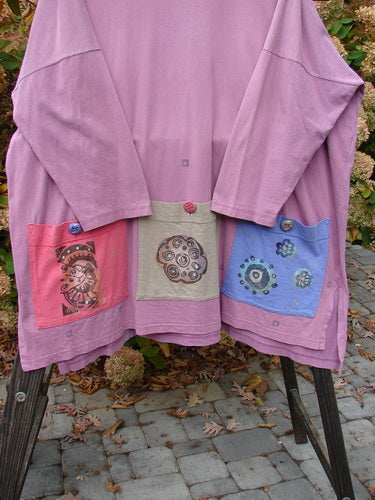 1997 Collage Top Petal Power Crocus OSFA: A pink jacket with different designs on it, featuring an A-lined shape, drop shoulders, vented sides, and oversized front pockets with vintage knot buttons. Made from mid-weight organic cotton.