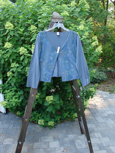 A blue jacket with a trailing garden vine theme paint, worn by a person, on a swinger.