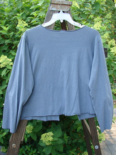 A medium weight cotton lycra long sleeved shrug in stormy blue. Features include an open front, trailing garden vine theme paint, and a varying hemline. Perfect condition. Size 1.