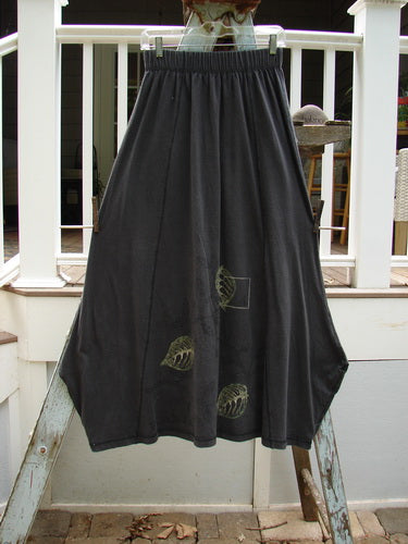 1998 Botanicals Gillyflower Skirt: A black skirt with a black design, made from mid-weight organic cotton. Features include a two-inch elastic waist, curvy exterior seams, generous hip measurement, and a specialized widening then narrowing hem. Adorned in the classic botanicals theme paint. Waist: 28-38 inches, hip: 60 inches, length: 38 inches.