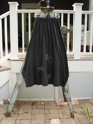 1998 Botanicals Gillyflower Skirt, Raven, Size 1: A black skirt on a ladder, with curvy exterior seams and a widening-narrowing hem.