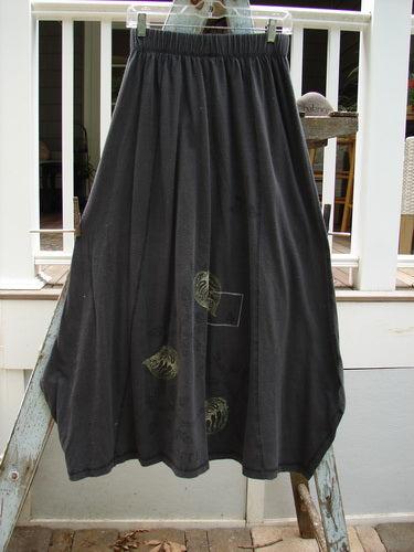 1998 Botanicals Gillyflower Skirt Leaf Raven Size 1: A black skirt with curvy exterior seams, a widening-narrowing hem, and botanical theme paint.