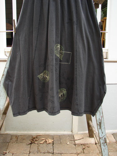 1998 Botanicals Gillyflower Skirt Leaf Raven Size 1: A black skirt adorned with green leaves, made from mid-weight organic cotton. Features include a curvy exterior, generous hip measurement, and a specialized widening then narrowing hem.