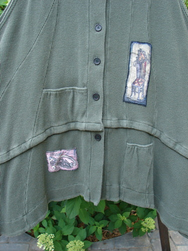 A close-up of a Barclay Thermal Patched Susset Vest in forest green, featuring two front pockets, a detachable bottom flounce, and wooden buttons.