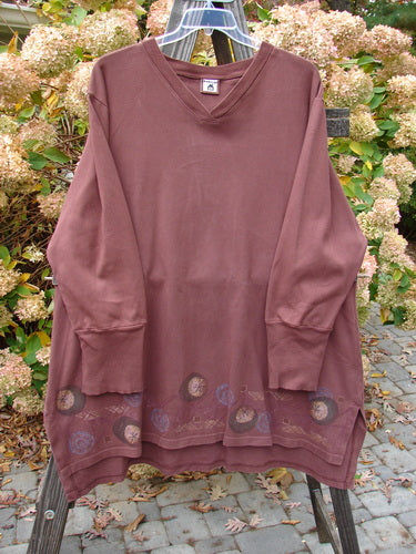 A long sleeved shirt on a clothes rack, Barclay Interlock V Neck Vented Tunic Top Moon Rise Sepia Size 2. Heavy weight cotton jersey interlock with a cross over ribbed neckline, shirttail hemline, and vented sides. Features magical moon rise theme paint and thicker ribbed lower sleeves.