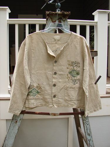 1999 Summercloth Hemp Crop Jacket Nature Cement Size 1: A shirt on a ladder with a logo close-up, metal ladder, and white pillar with black border.