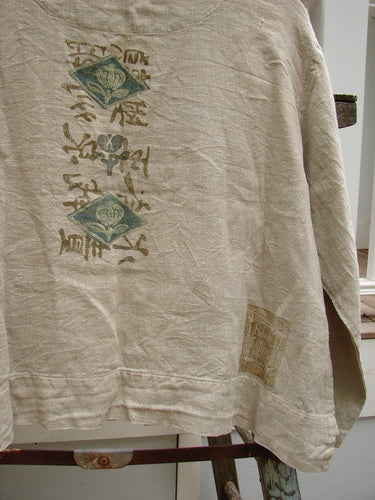 1999 Summercloth Hemp Crop Jacket Nature Cement Size 1: A close-up of a shirt with a nature-inspired paint design, metal button front, and double front drop billowy pockets.