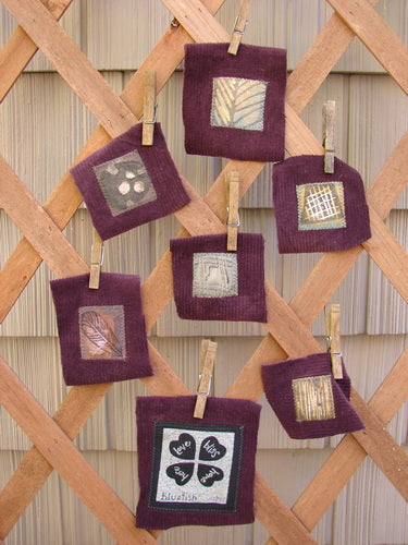 A group of fabric squares on a wooden lattice, part of the PMU 1999 Fall Woods Patch Set Total 7.