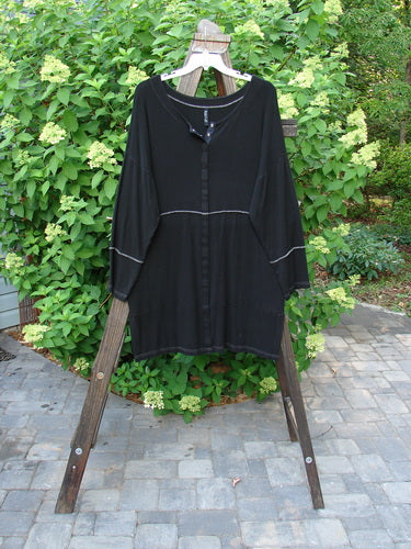 A black Snap Reverse Stitch Contrast Cardigan on a wooden rack, featuring a full snap front and horizontal panels. Size 2.