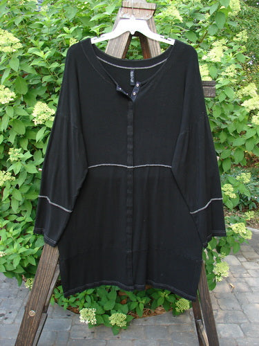 A black Snap Reverse Stitch Contrast Cardigan on a wooden rack.