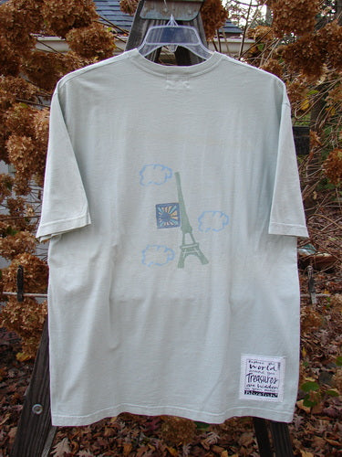 A white t-shirt with a picture of the Eiffel Tower, featuring a postcard theme paint and the Blue Fish signature patch. Size 1, from the 2000 Summer Collection in Dune Grass.
