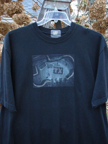 2000 Short Sleeved Tee Austin Texas Black Size 1: A black t-shirt with a picture on it, featuring a thicker ribbed neckline and a straighter shape. Classic Austin Texas theme paint and the best signature Blue Fish patch.