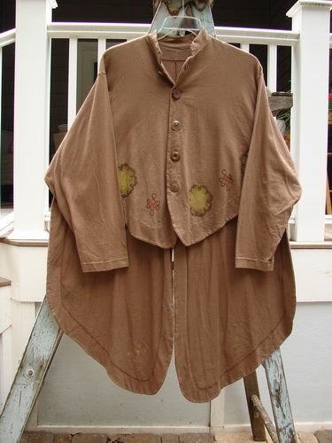 A 1997 Tails Jacket from the Holiday Winter Collection in Mandorla. Features include oversized shiny brown buttons, a mandarin style mock neckline, and front and back tails with lovely lacing. Flared hip tails and a day cloud theme paint add to its special look. Bust: 58, Waist: 60, Sleeves: 28, Front Length: 23, Back Tails: 42.