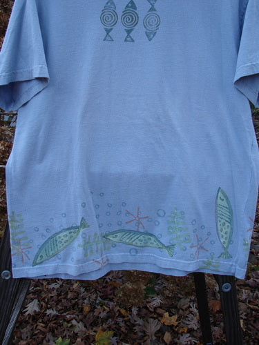 1999 Short Sleeved Tee Fish Triple Water Size 1: A blue shirt with fish painted on it, featuring a rolled ribbed neckline and a straighter shape. Made from medium weight organic cotton jersey.