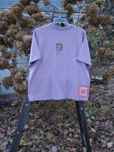 1997 Short Sleeved Tee Five Shell Jasmine Size 1: A purple t-shirt with a logo on it, featuring a thicker ribbed neckline and a slightly shorter, boxier shape. Made from medium weight organic cotton jersey.