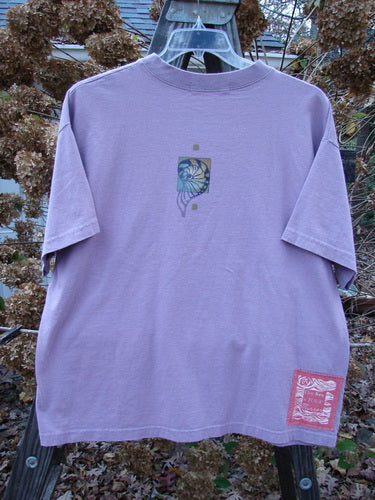 1997 Short Sleeved Tee Five Shell Jasmine Size 1: A purple t-shirt with a graphic design of five shells. Made from organic cotton jersey, this tee features a ribbed neckline and a shorter, boxier shape. Perfect condition.