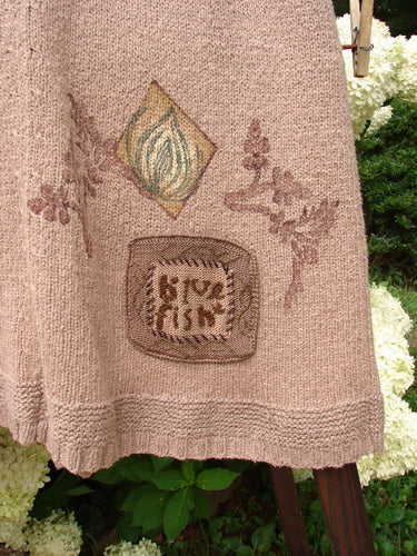 1998 Teton Sweater Vest with alternative stitching, ceramic buttons, and a tiny twig theme. A close-up of a cloth with a knitted sign, wooden slat, and flower.