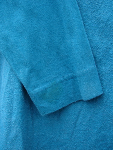 A close-up of a Barclay Cotton Sleeve Hemp Jacket in aqua, featuring a rounded boatneck, oversized painted pockets, and slim organic cotton sleeves.
