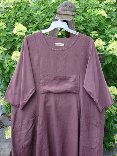 Barclay Linen Cotton Sleeve Upper Pocket Dress Unpainted Red Plum Size 2: A purple shirt on a swinger, featuring a rounded neckline, sectional panels, and a horizontal upper bodice pocket.