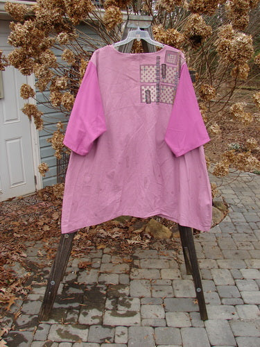 A Barclay Cotton Sleeve Hemp Linen Sectional Dress in Rose, featuring a pink shirt on a swinger. The dress has a sectional upper with a downward curved empire waist seam, a varying and pleated A-line shape, and a slightly shallow rounded neckline. The contrasting cotton three-quarter length sleeves add a unique touch. Perfect for a vintage clothing enthusiast.