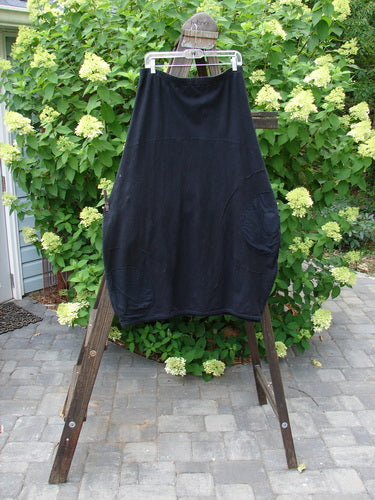A black Barclay Cotton Hemp Panel Pocket Circle Skirt on a clothesline, featuring a full elastic waistline, lower bell accent, and deep front entry banded upper pockets. Unpainted and in perfect condition. Size 2. Length: 39 inches.