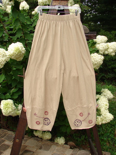 Image alt text: 1996 Boulevard Pant Star Travel Dune Size 1: A pair of pants with a floral design, featuring overlapping painted cuffs and cloth covered buttons.