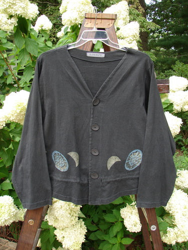 1997 Treehouse Jacket Many Moons Cast Iron Size 2: A black sweater with blue moon designs on it, featuring a double paneled V-neck, button line, and drawcord flounce.