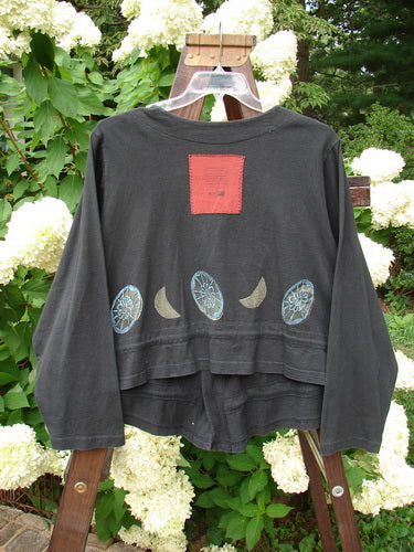 1997 Treehouse Jacket Many Moons Cast Iron Size 2: A black shirt with a patch on it, featuring a red square and a logo.