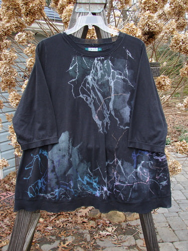 A black shirt with blue and purple designs, featuring a netted flutter neckline and three-quarter length sleeves. Perfect condition, made from mid-weight organic cotton. Size 2.