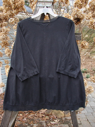 A Barclay Flutter Net A Lined Tee Top in Black, Size 2, on a clothes rack. Three-quarter sleeves with a netted flutter. Lightening theme paint on the lower hem.