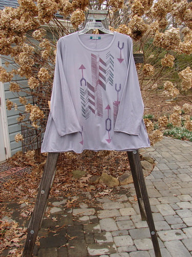 A Barclay Long Sleeved A Lined Tee Top in Mottled Lavender, featuring a rounded neckline, cozy long sleeves, and sweet curled edgings. The tee top showcases a swinging A-line shape with arrow side theme paint.