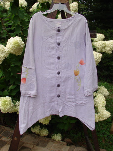 2000 Woven Hemp Sophia Cardigan Tulip Lilac Size 1: A long white shirt with flowers on it, featuring a lovely rounded neckline, full front button closure, and a varying hemline.